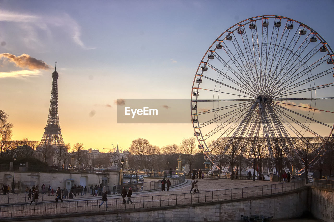 The big wheel and eiffel tower against sky during sunset