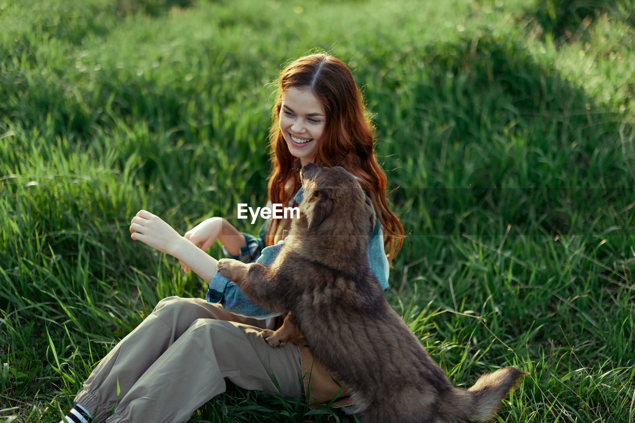 portrait of young woman with dog on grassy field