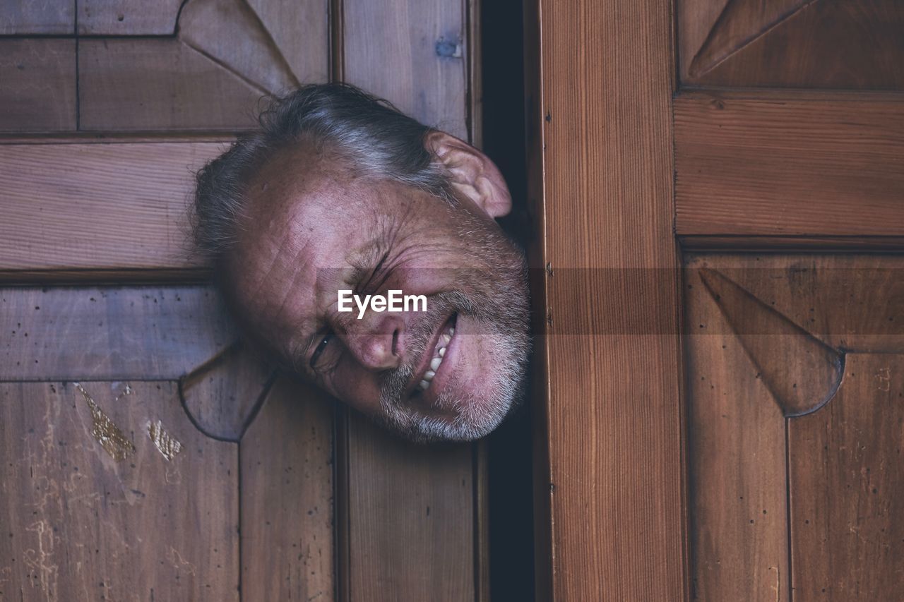 Portrait of senior man peeking through door