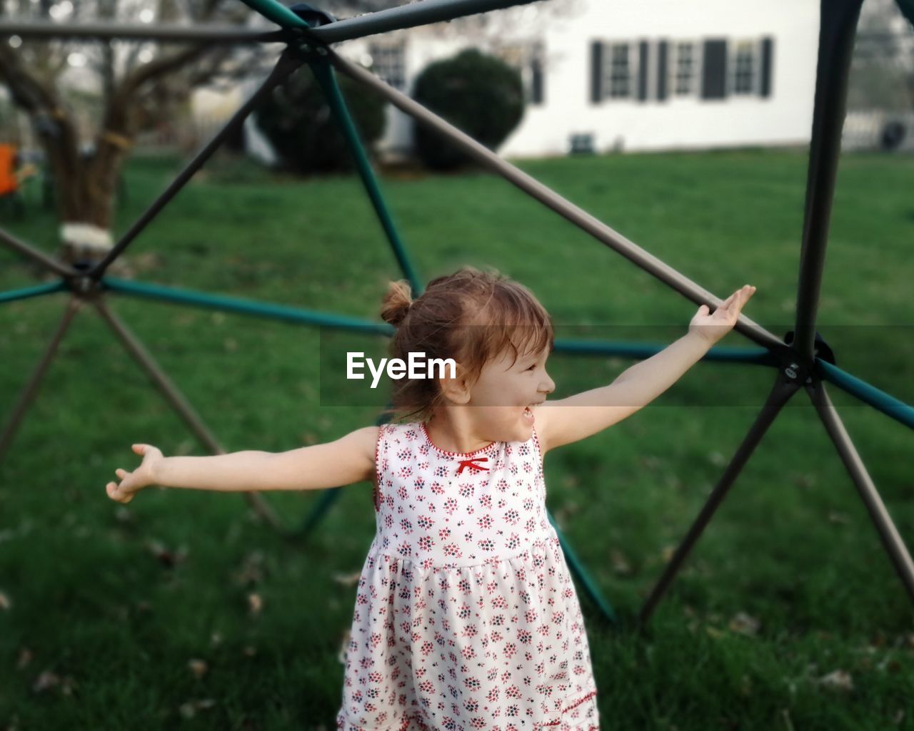 Cheerful girl standing against play equipment at park