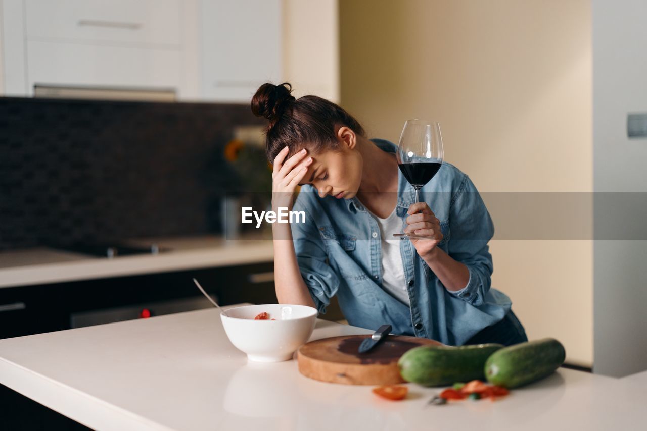 young woman using mobile phone while sitting on table at home