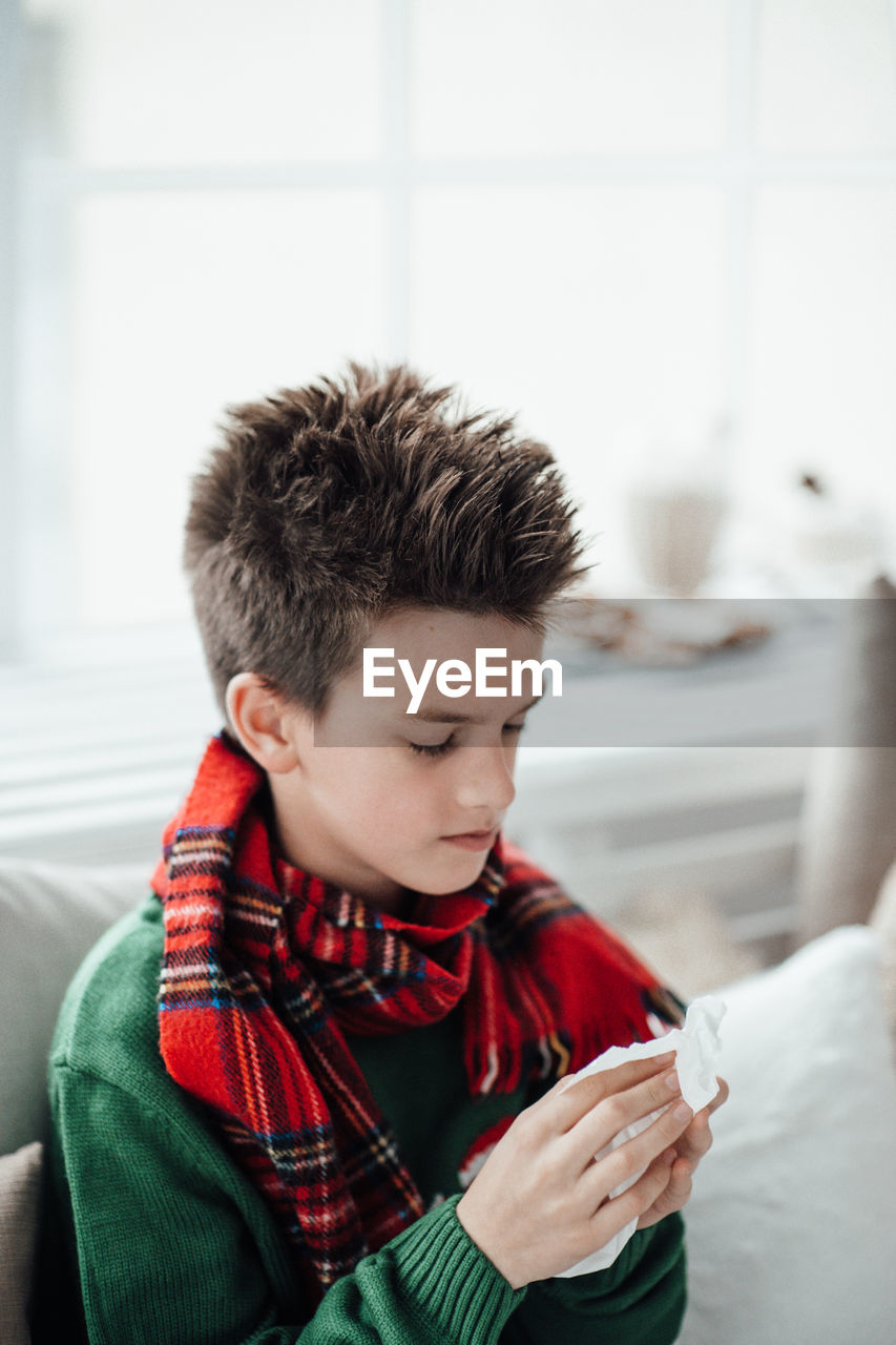 Close-up of boy sneezing at home