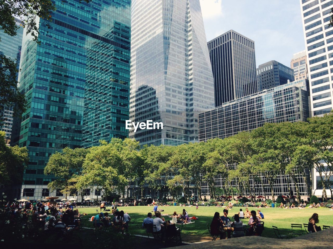 People relaxing at bryant park against buildings in city