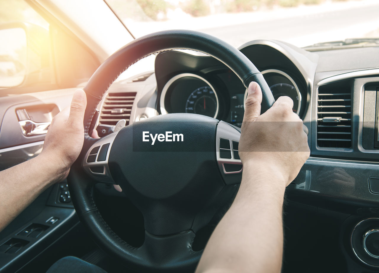 Cropped hands of man driving car