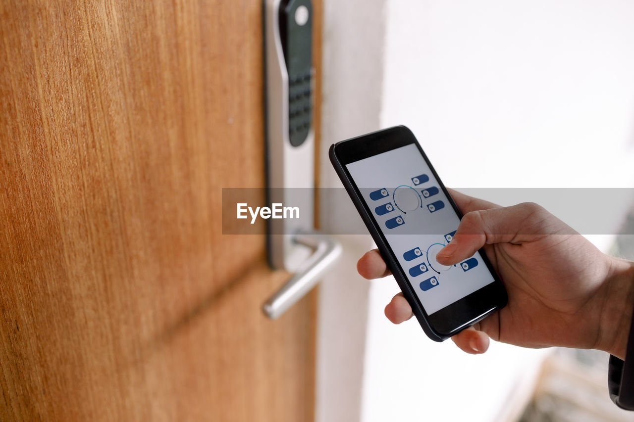 Cropped hand of unlocking door through smart phone