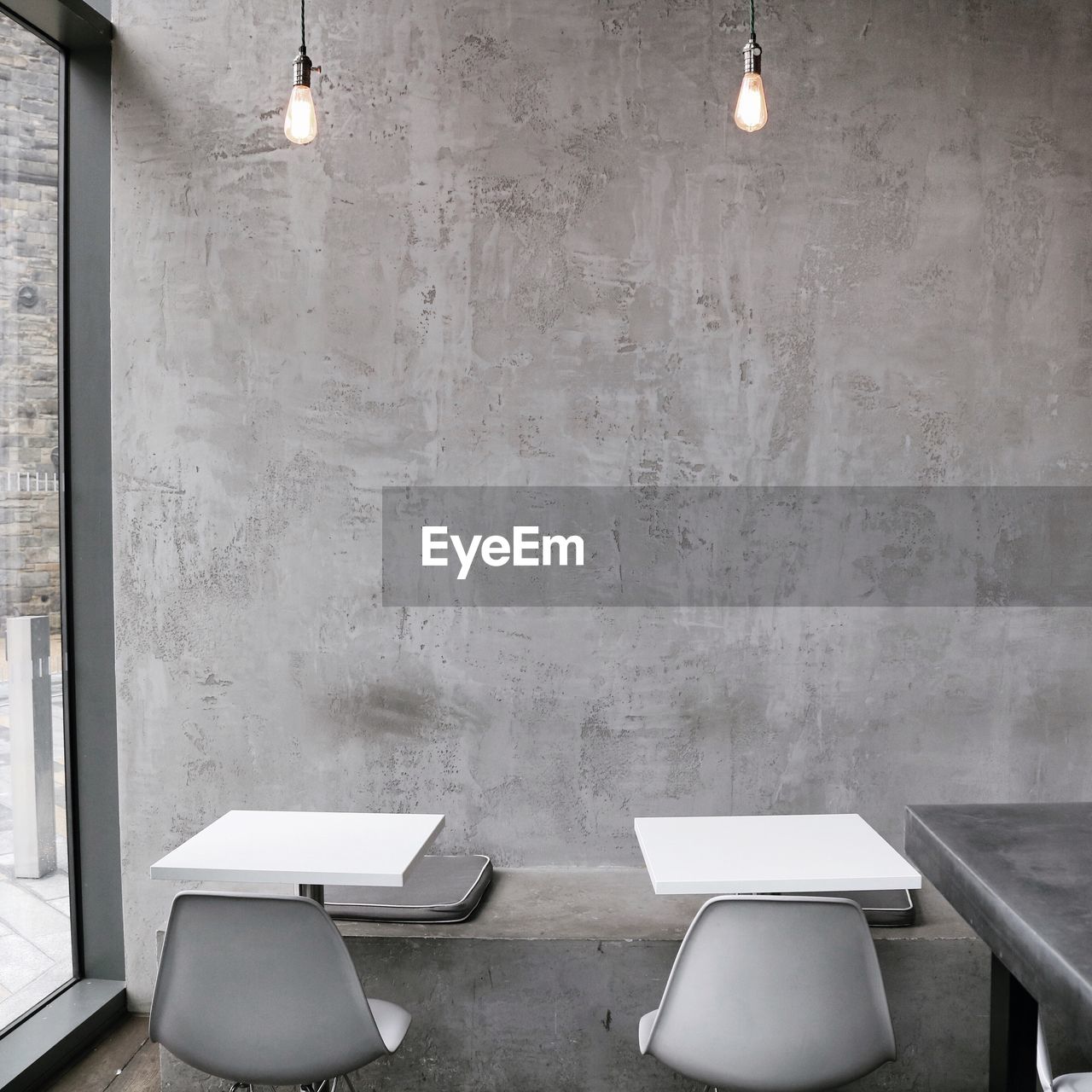 EMPTY CHAIRS AND TABLE IN ILLUMINATED ROOM