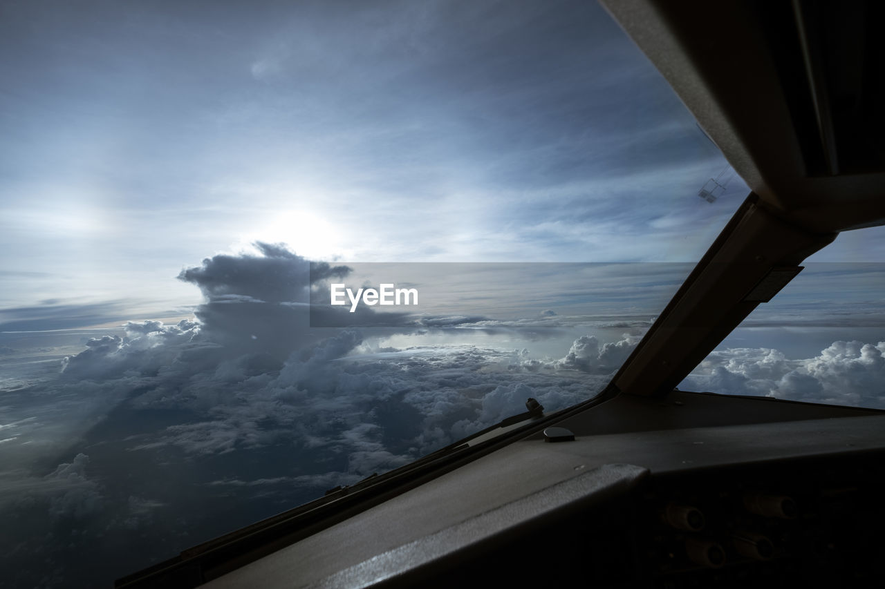 AIRPLANE WINDOW OVER SNOWCAPPED MOUNTAINS AGAINST SKY