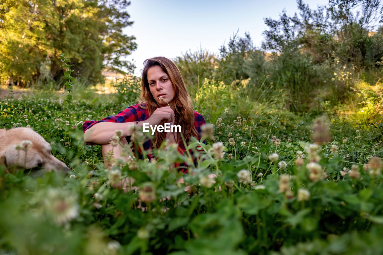 PORTRAIT OF BEAUTIFUL WOMAN SITTING ON FIELD