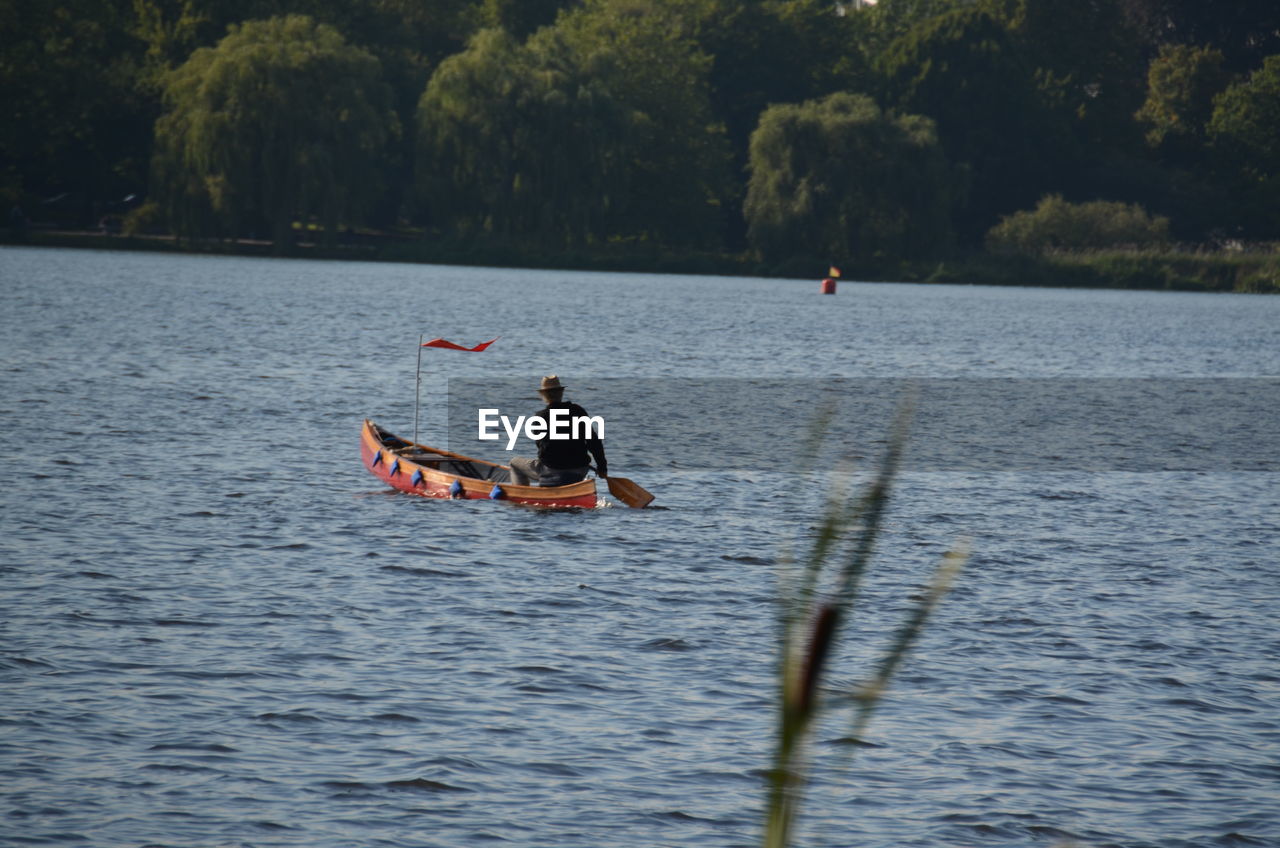 Rear view of man rowing boat in river