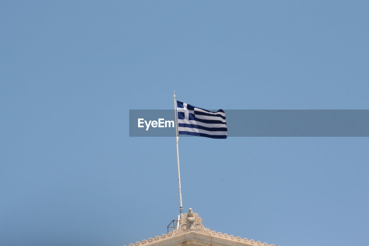 Low angle view of greek flag against clear blue sky