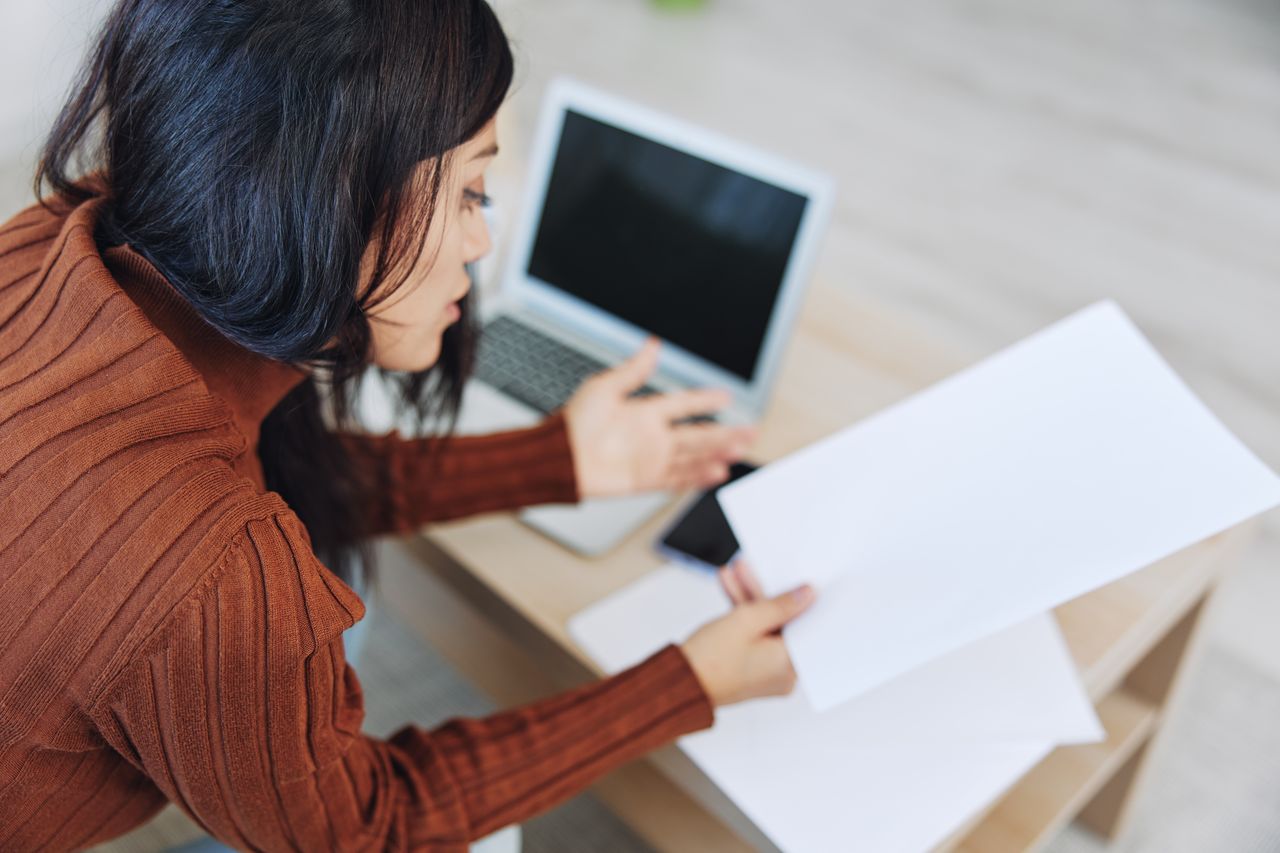 rear view of woman using laptop while sitting on table