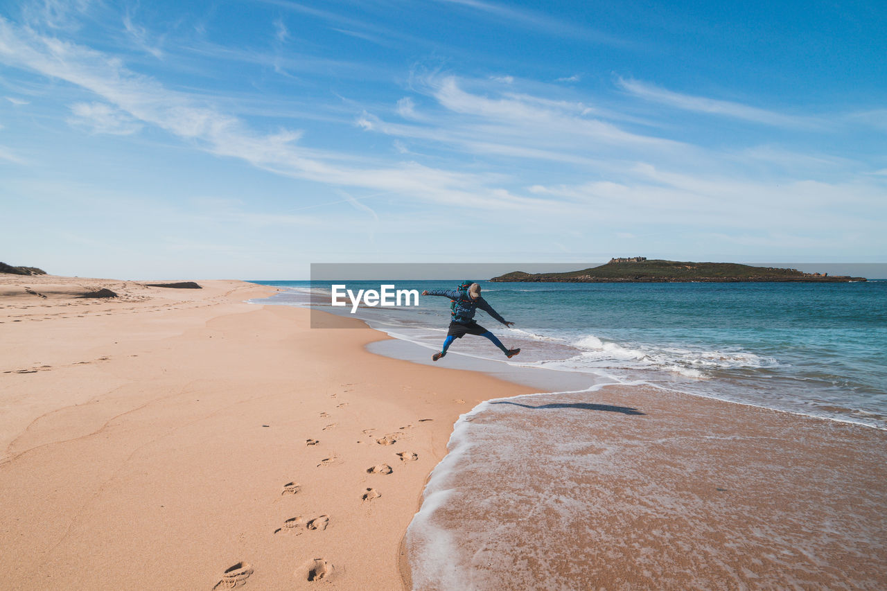 rear view of woman standing at beach against sky