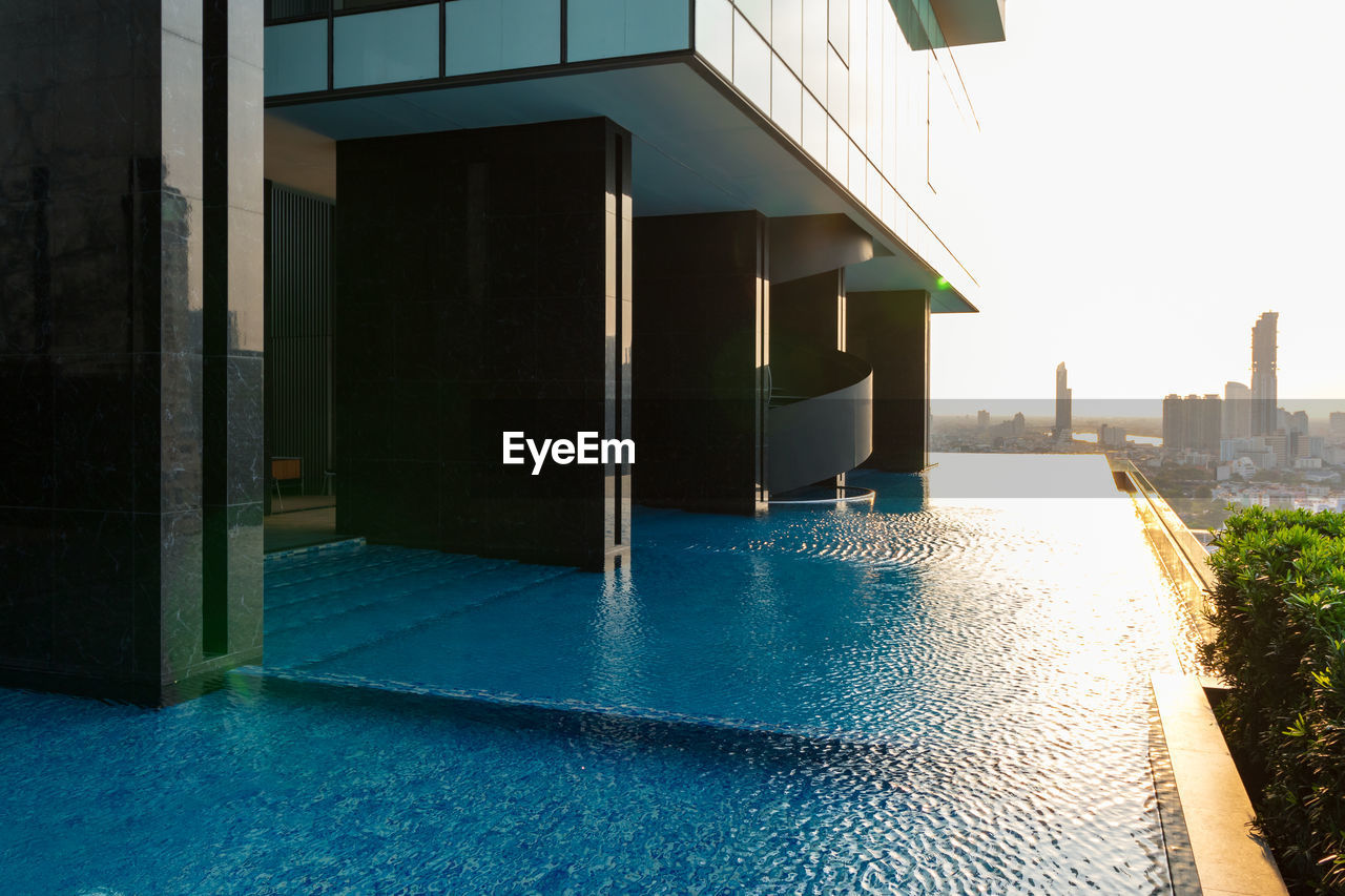 BUILDINGS BY SWIMMING POOL AGAINST CLEAR SKY