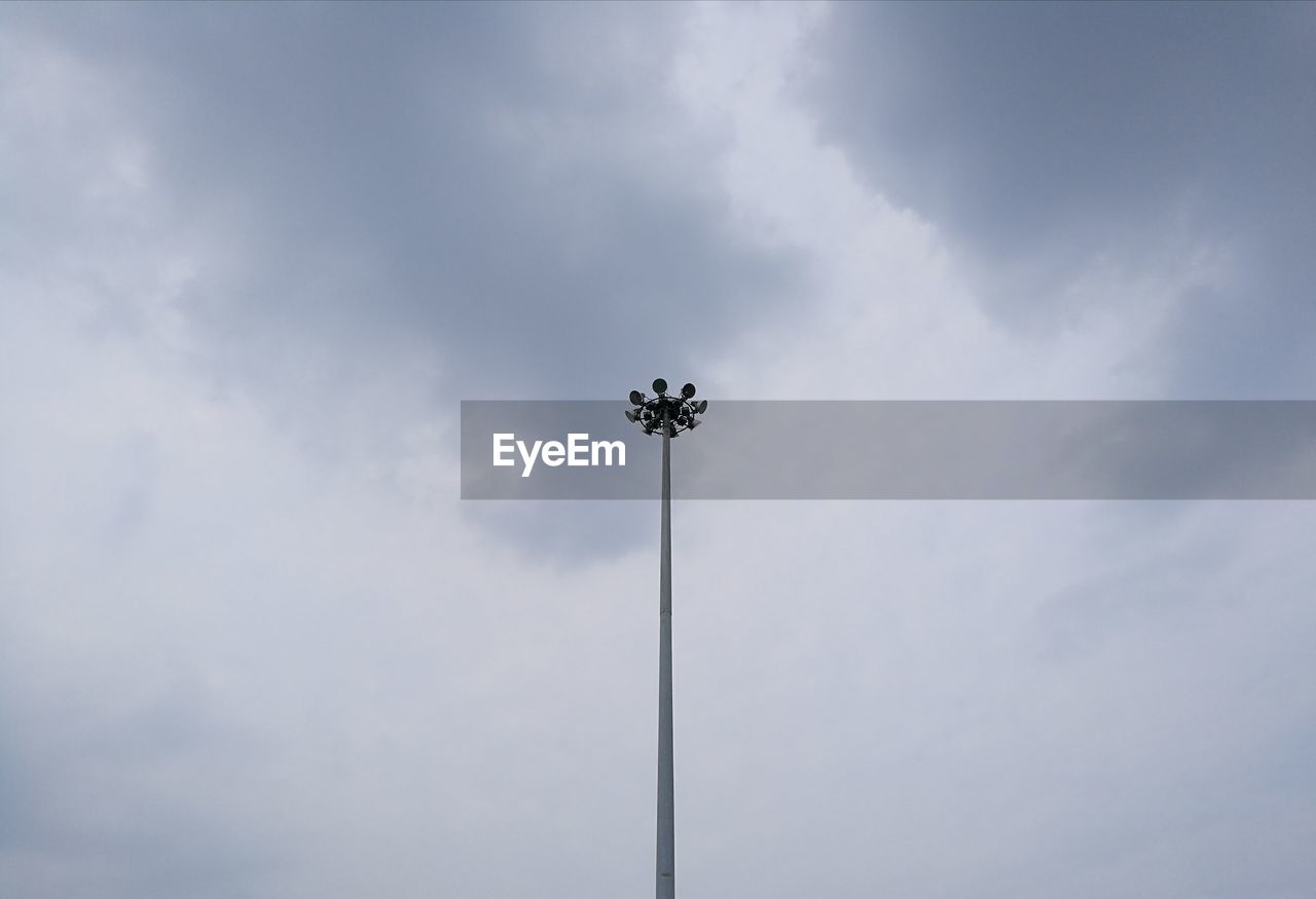 LOW ANGLE VIEW OF FLOODLIGHT AGAINST CLOUDY SKY