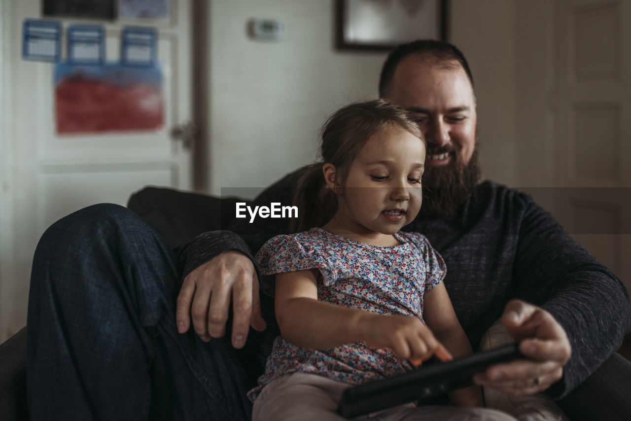 Close up of dad and young daughter playing on tablet during isolation