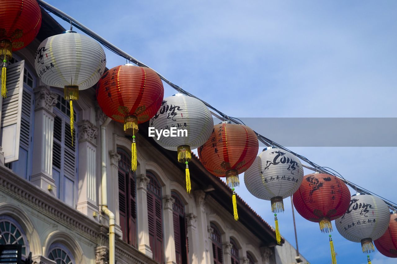 Low angle view of chinese lanterns hanging by building against sky