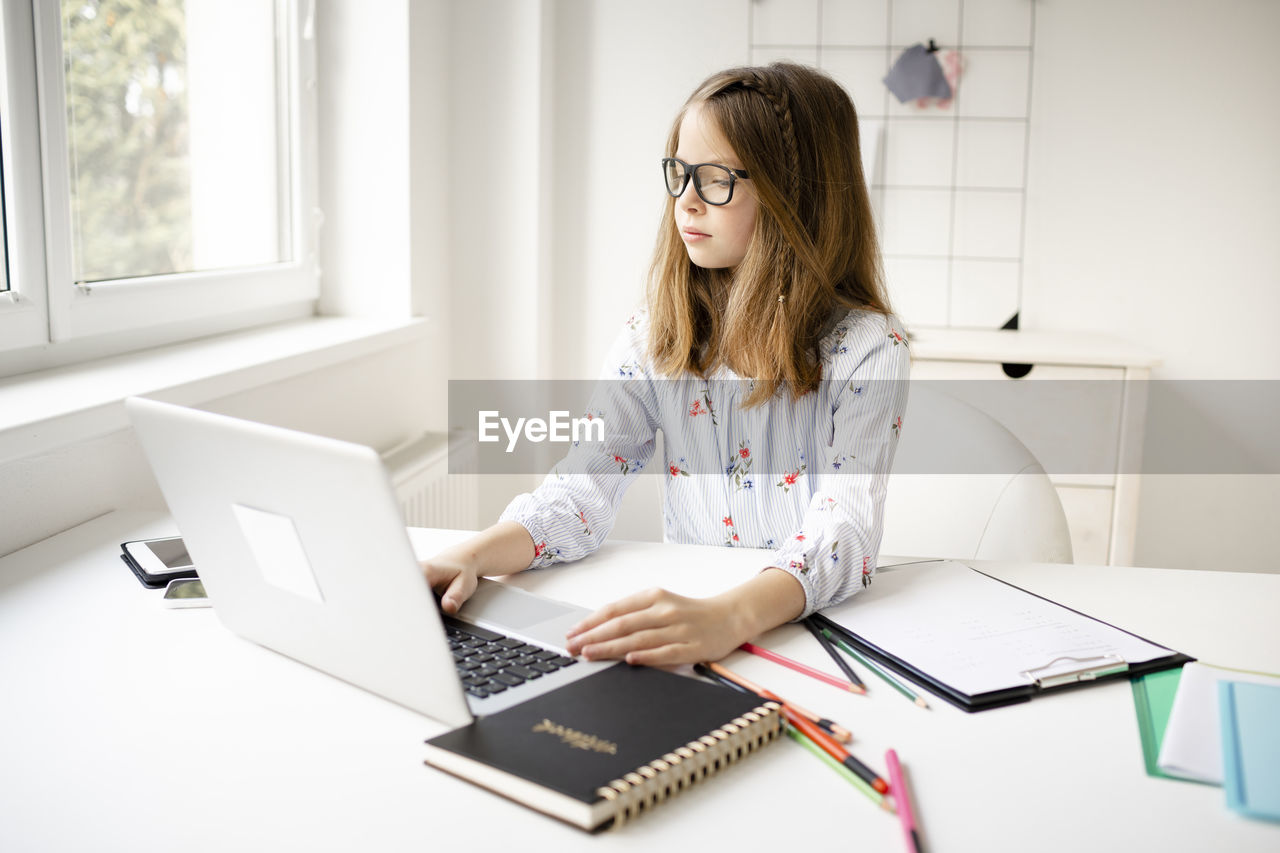 Woman using mobile phone while sitting on table