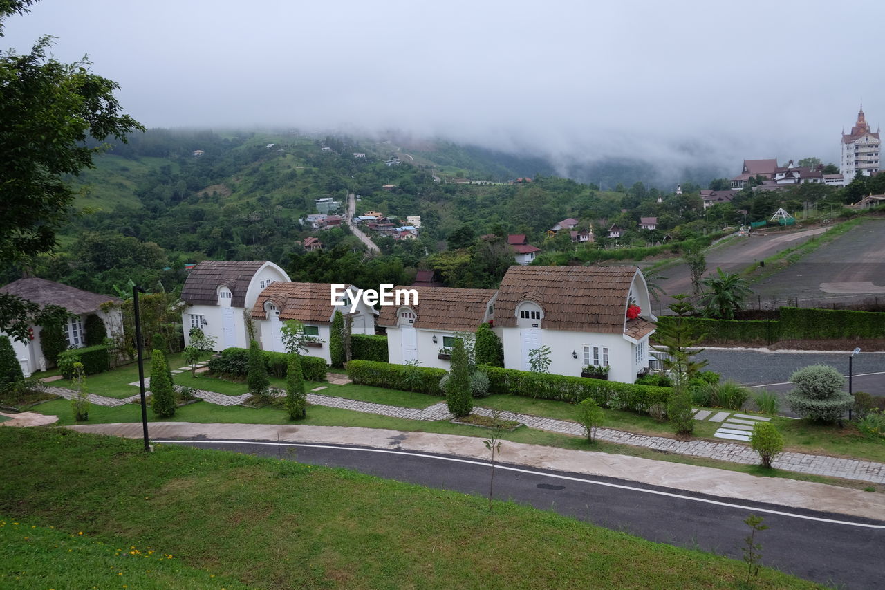 HOUSES BY ROAD AMIDST BUILDINGS AGAINST SKY