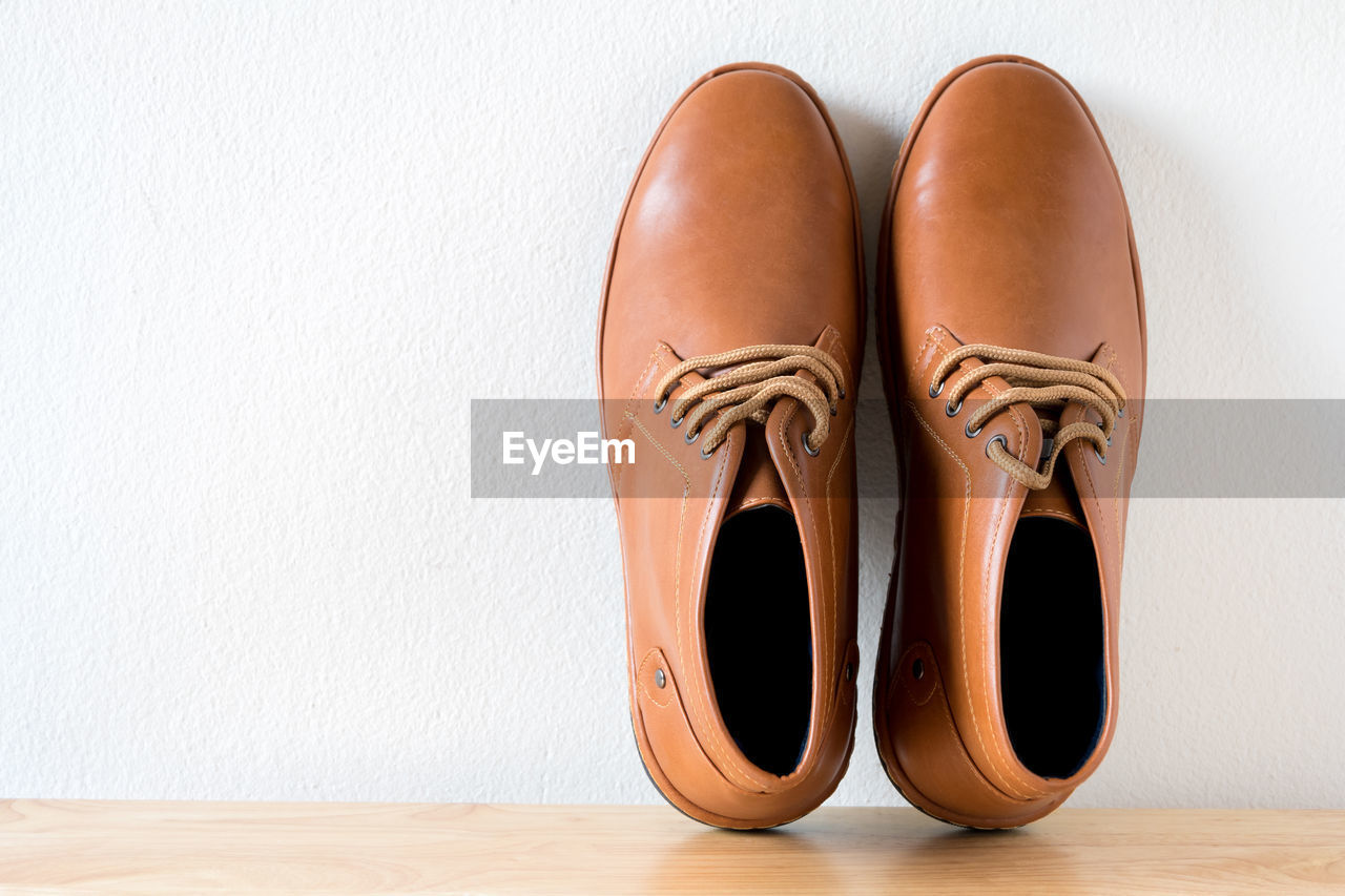 Close-up of brown shoes on table against white wall