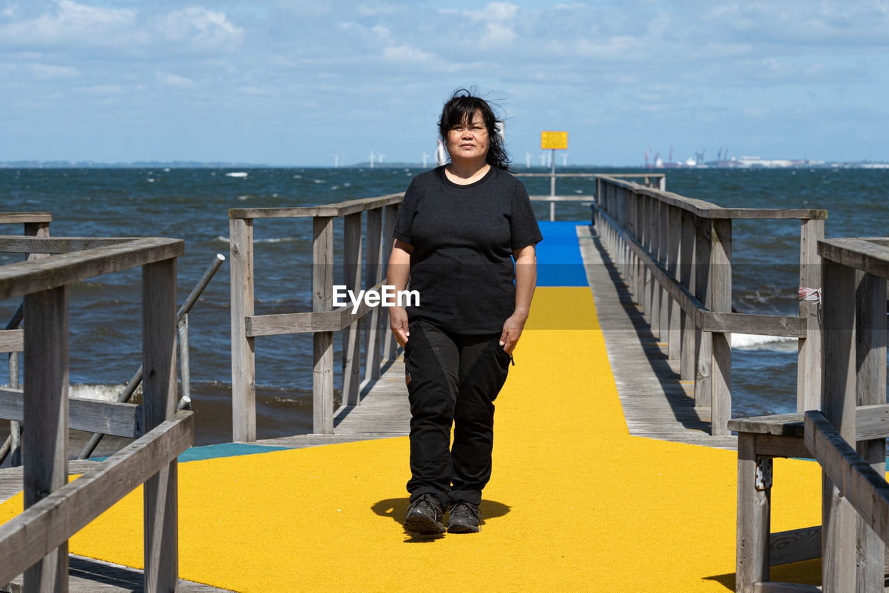 Full length of woman standing on pier against sea