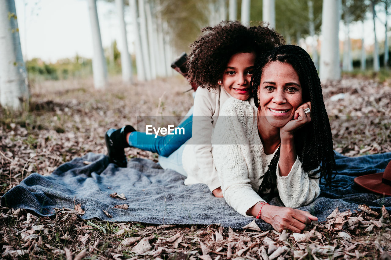 Portrait of smiling daughter lying with mother on land