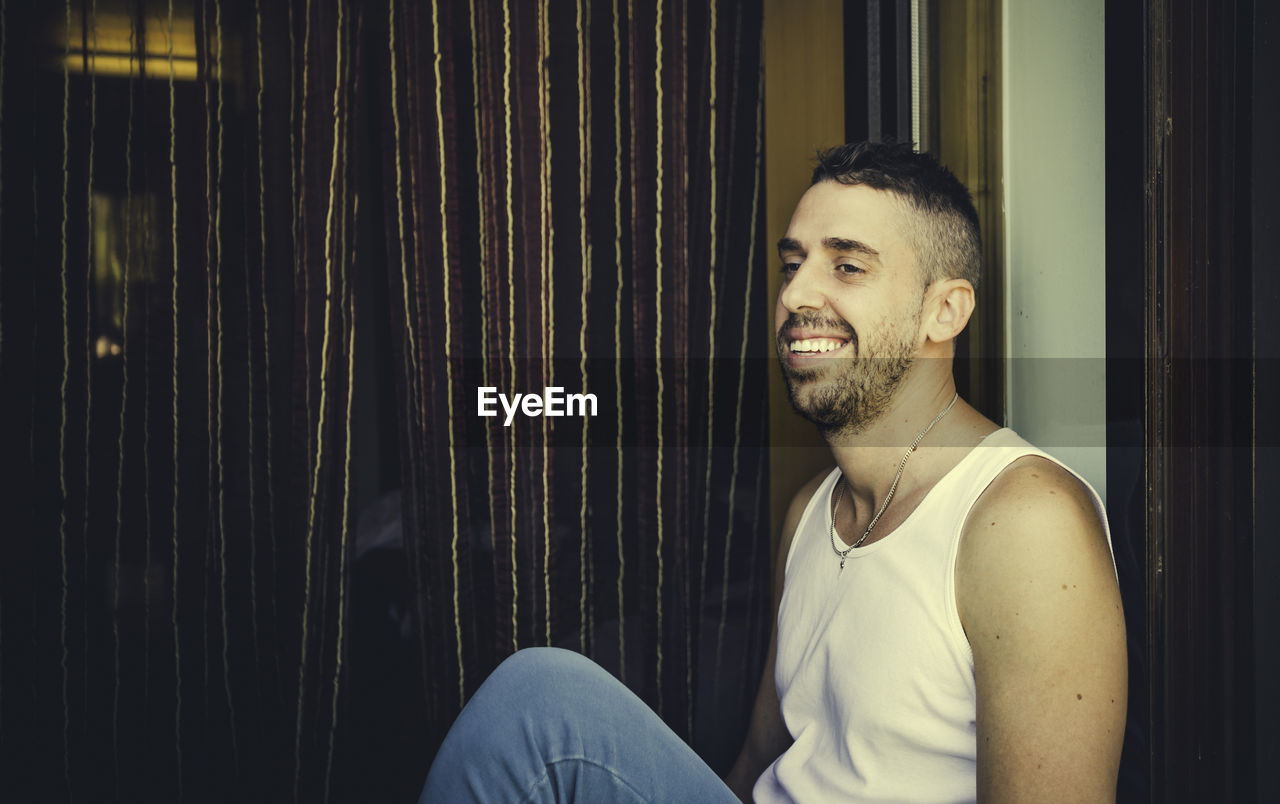 Young looking away while man sitting against window