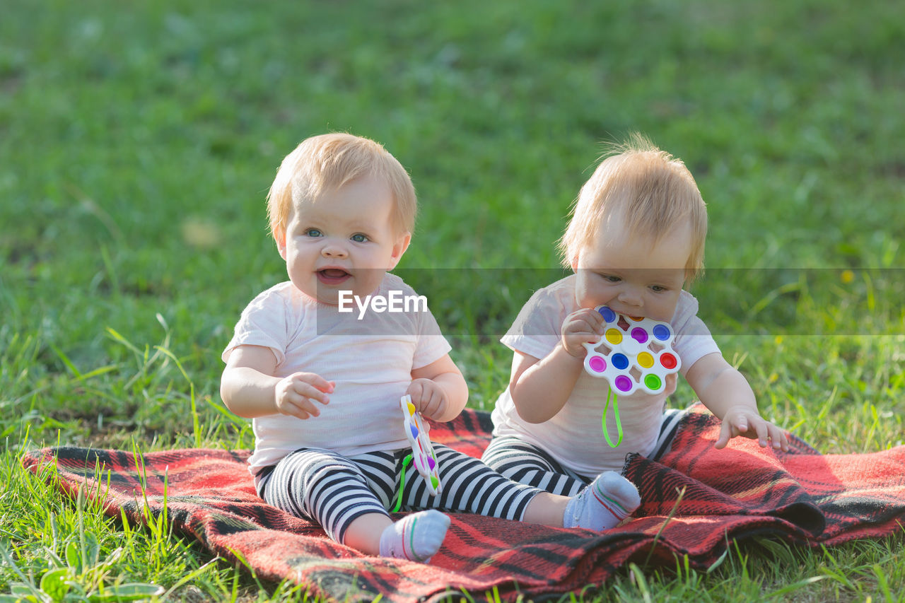 Siblings sitting on field