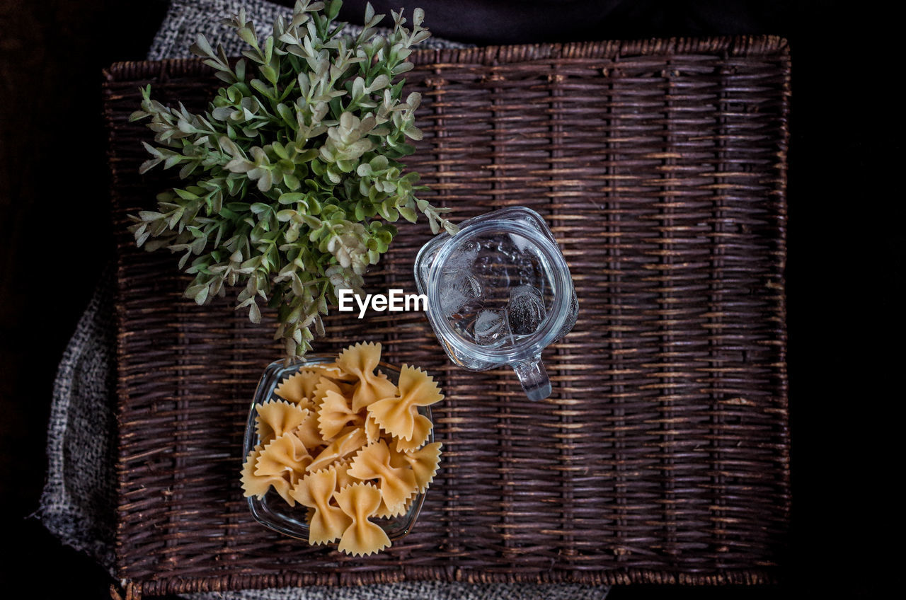 Directly above shot of farfalle pasta and drinking water on wicker mat