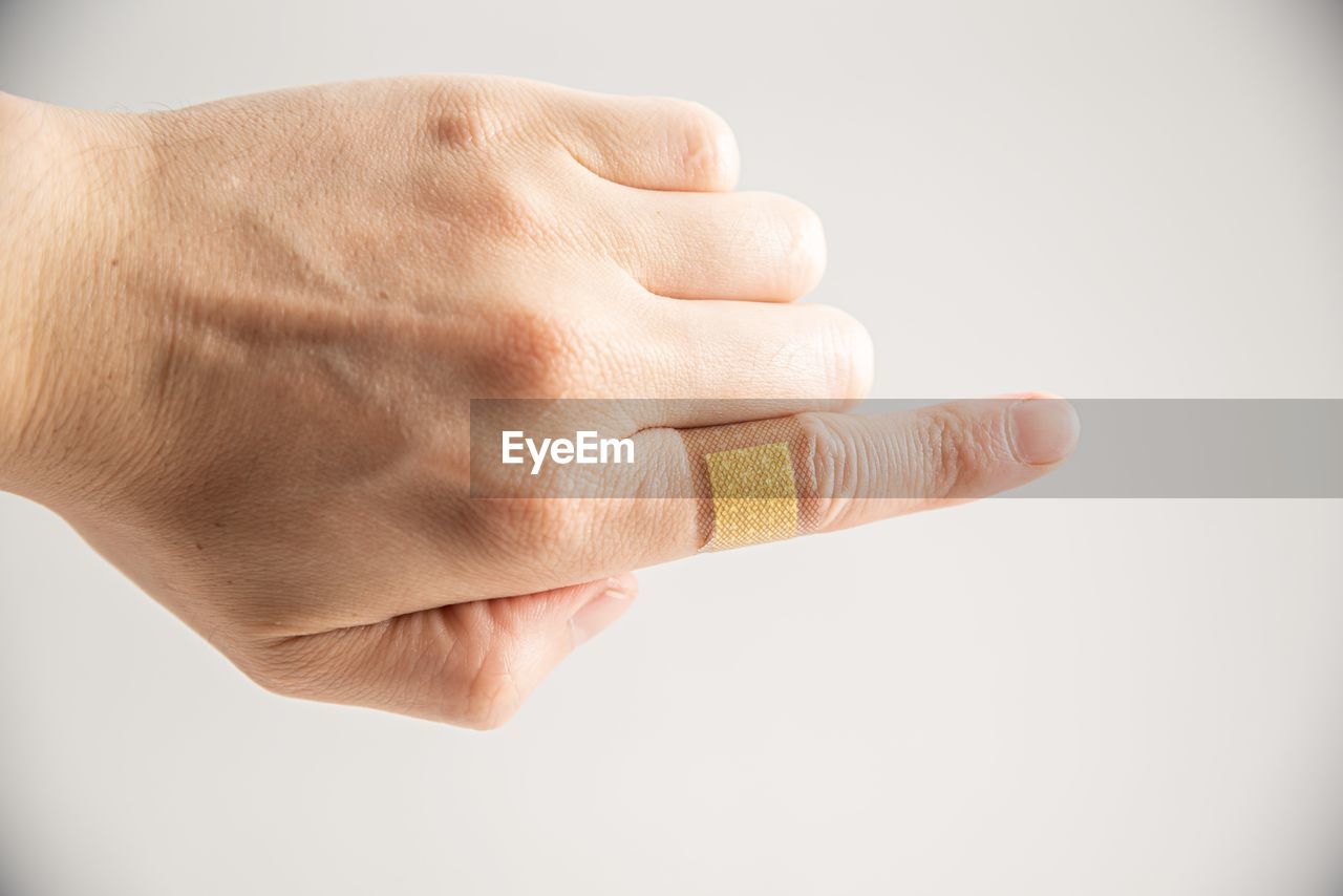 CLOSE-UP OF HANDS OVER WHITE BACKGROUND