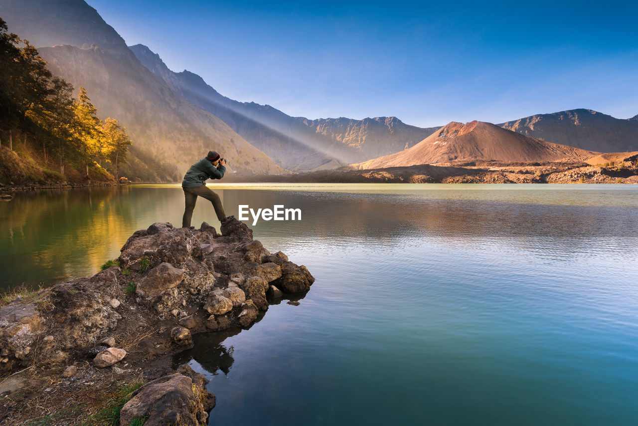 Man photographing sea through camera while standing on cliff