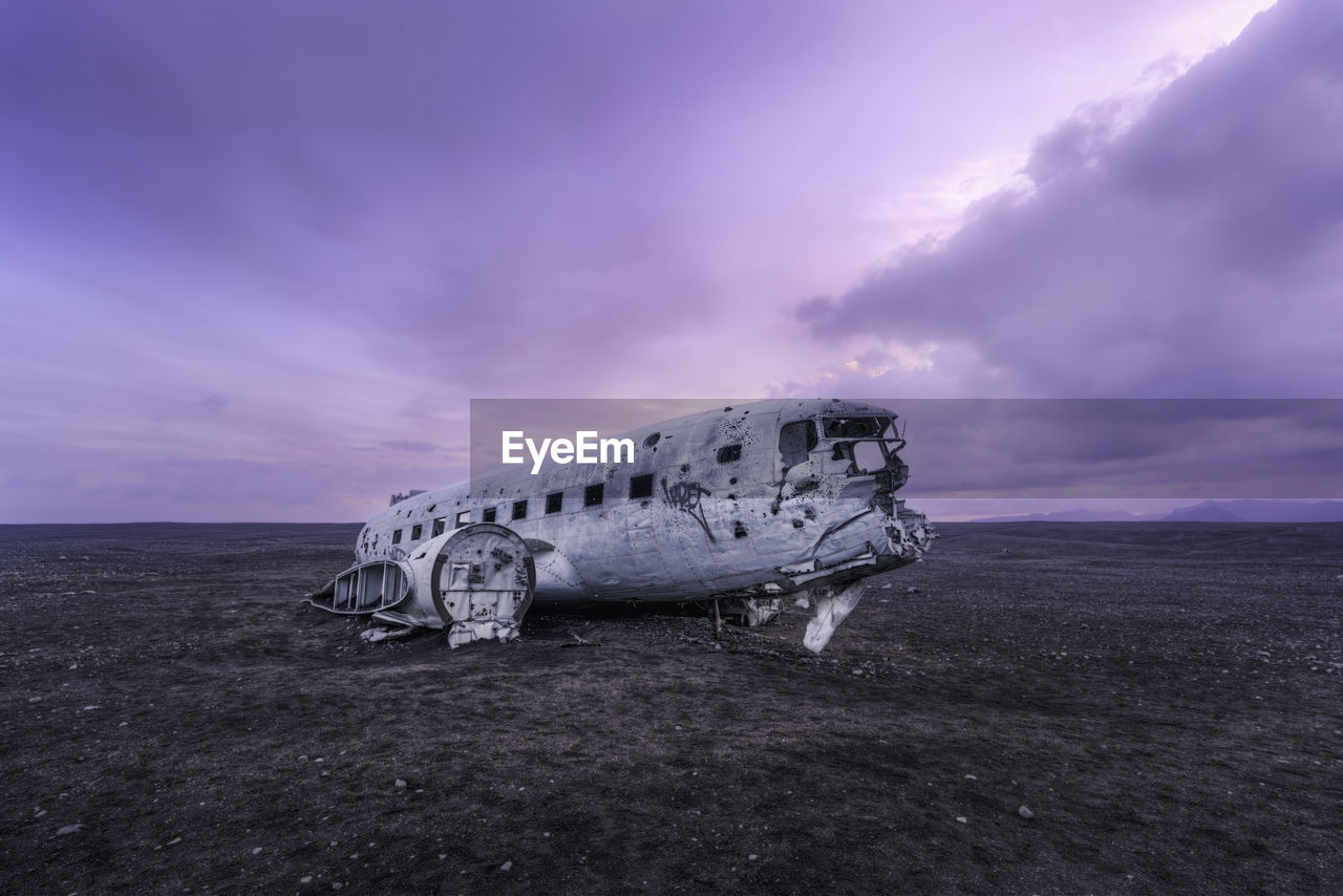 Abandoned airplane at beach against sky