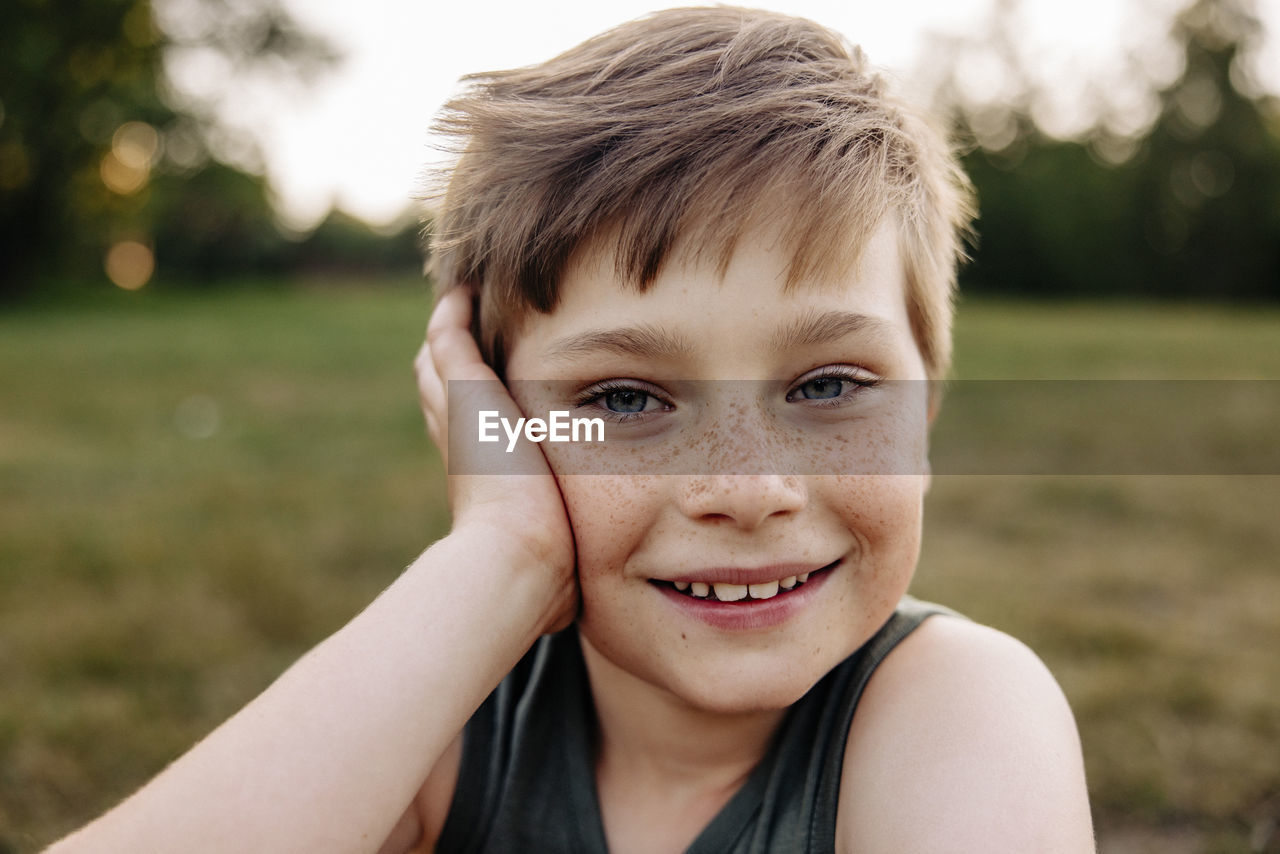 Portrait of happy boy with freckles leaning on elbow