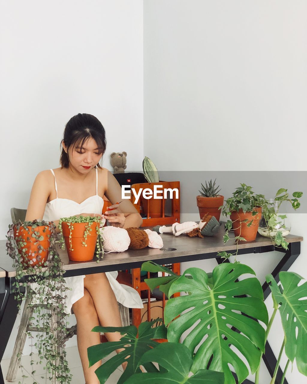 Young woman sitting by potted plant on table