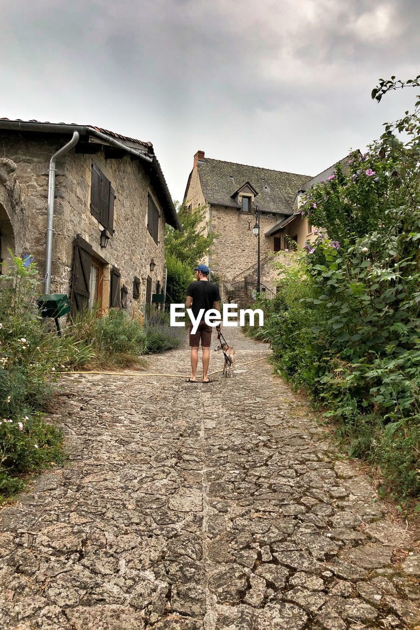 REAR VIEW OF PEOPLE WALKING OUTSIDE HOUSE AGAINST SKY