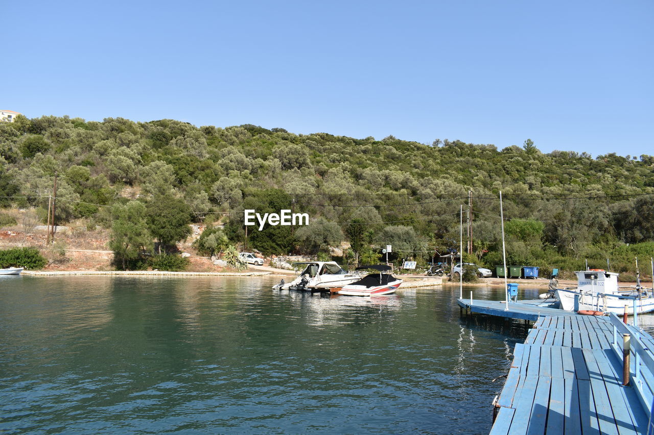 water, nautical vessel, tree, transportation, nature, sky, clear sky, plant, mode of transportation, sea, land, blue, travel, no people, boat, vehicle, scenics - nature, day, travel destinations, beauty in nature, tranquility, sunny, beach, moored, bay, landscape, environment, vacation, outdoors, tourism, holiday, ship, boating, tranquil scene, trip, harbor, idyllic, non-urban scene, waterfront, architecture, sunlight, marina, watercraft, pier, forest, coastline, yacht