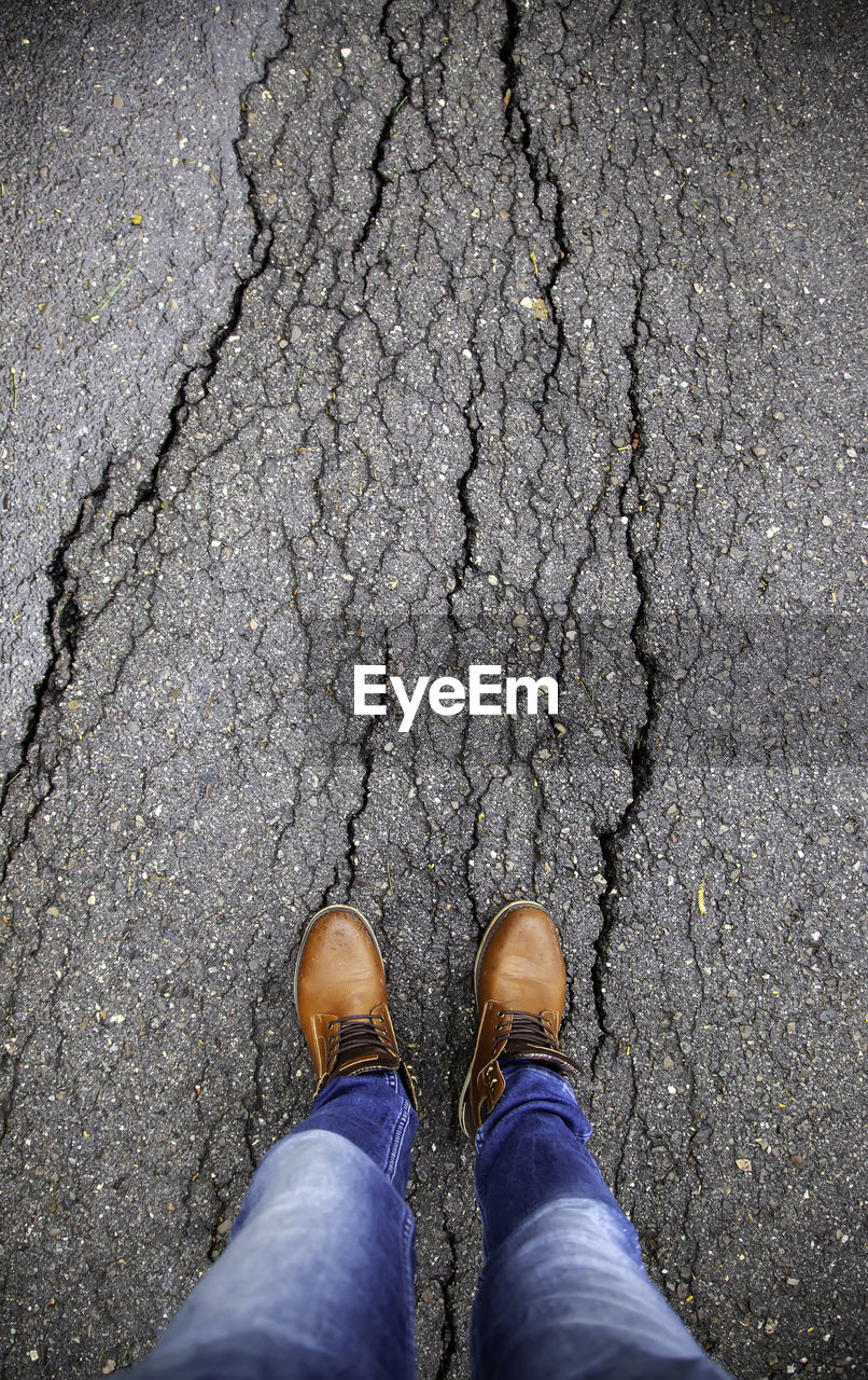 Low section of man standing on cracked street