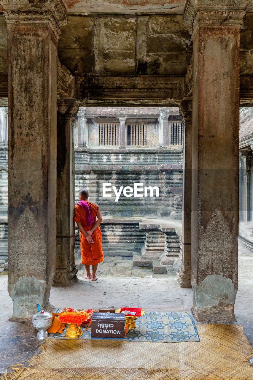 Rear view of monk standing in temple