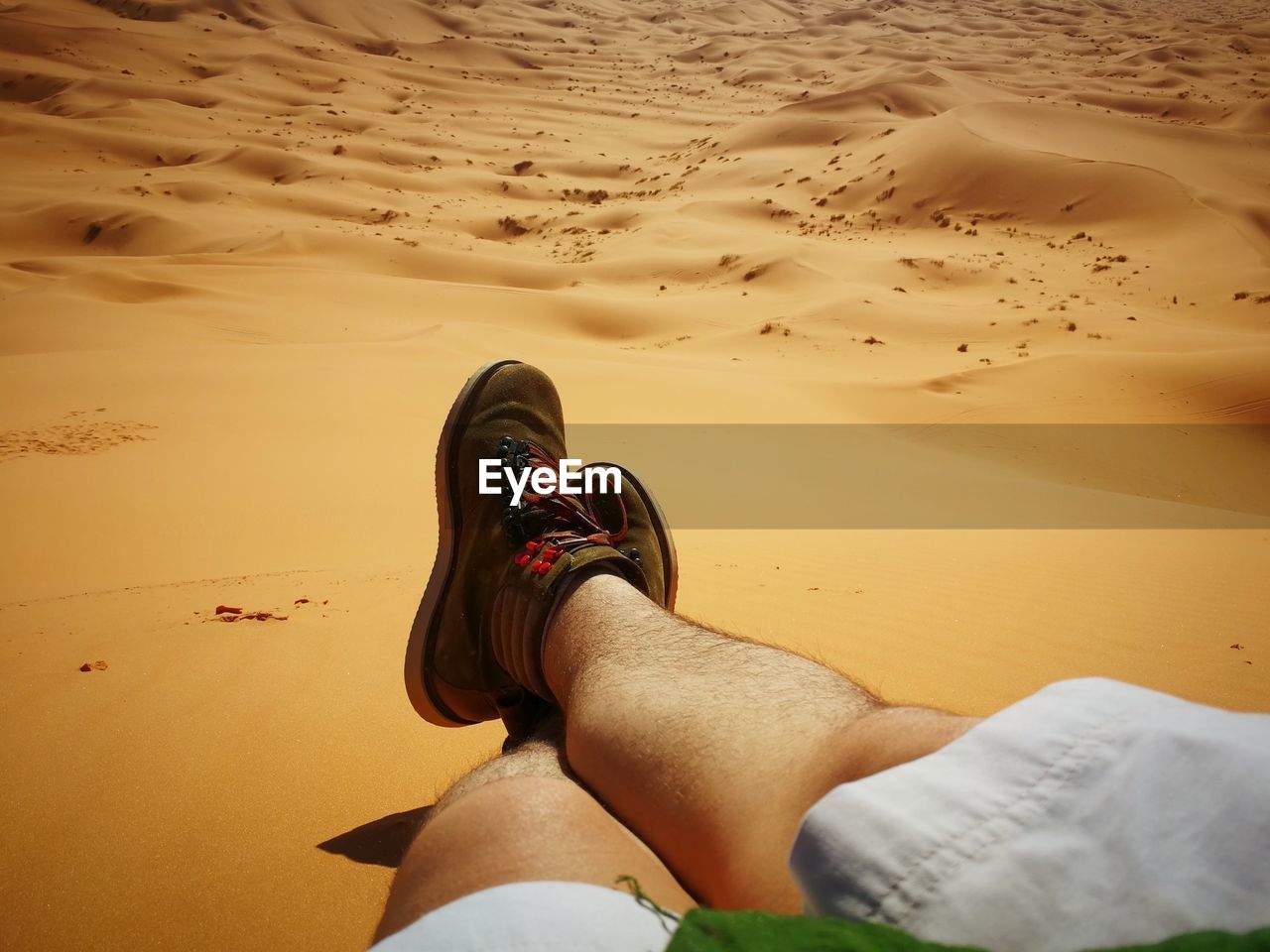 Low section of man relaxing at desert