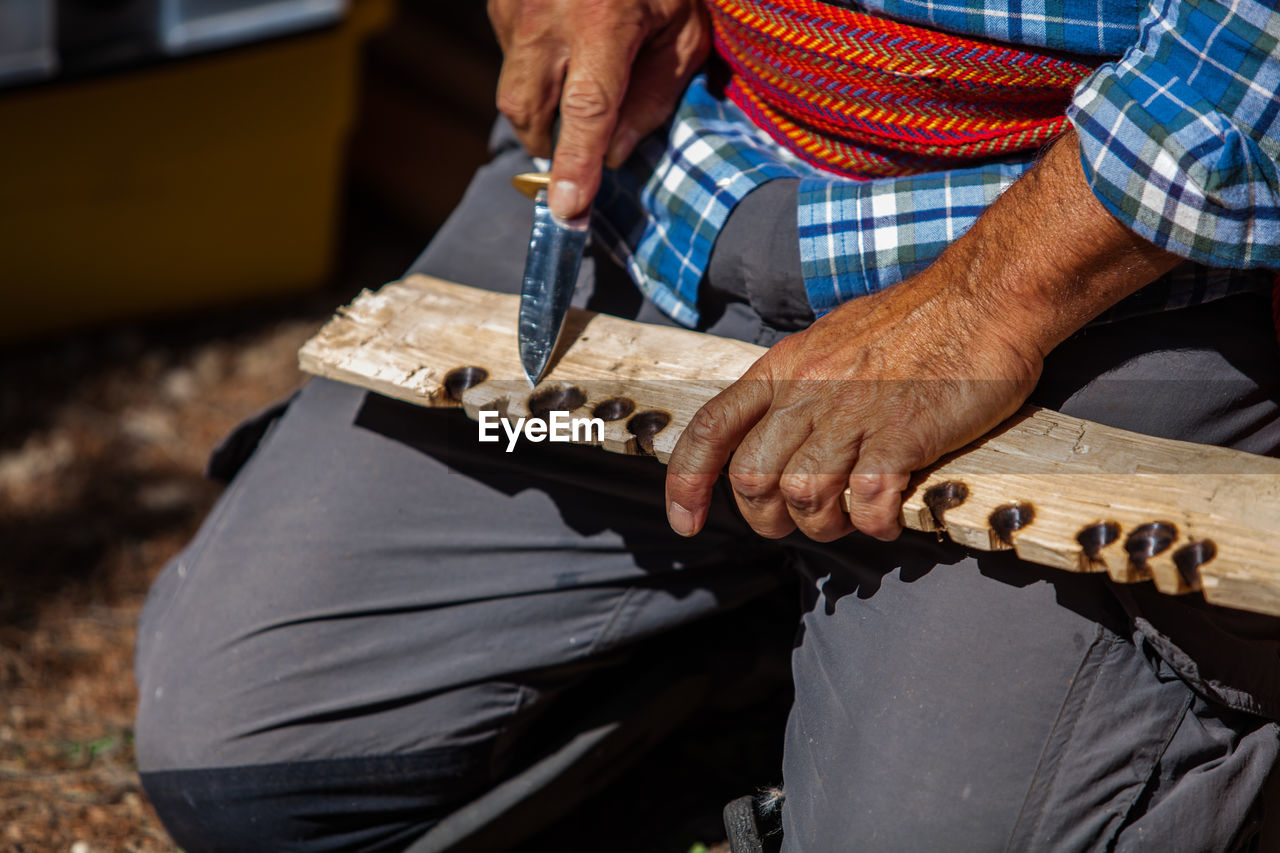 Midsection of man working on wood