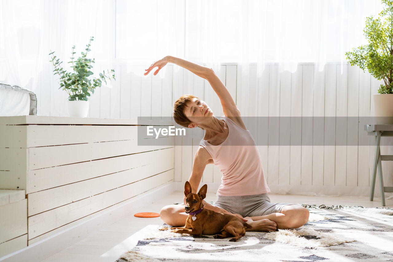 Woman doing yoga with her dog, enjoy and relax with yoga at home, relax