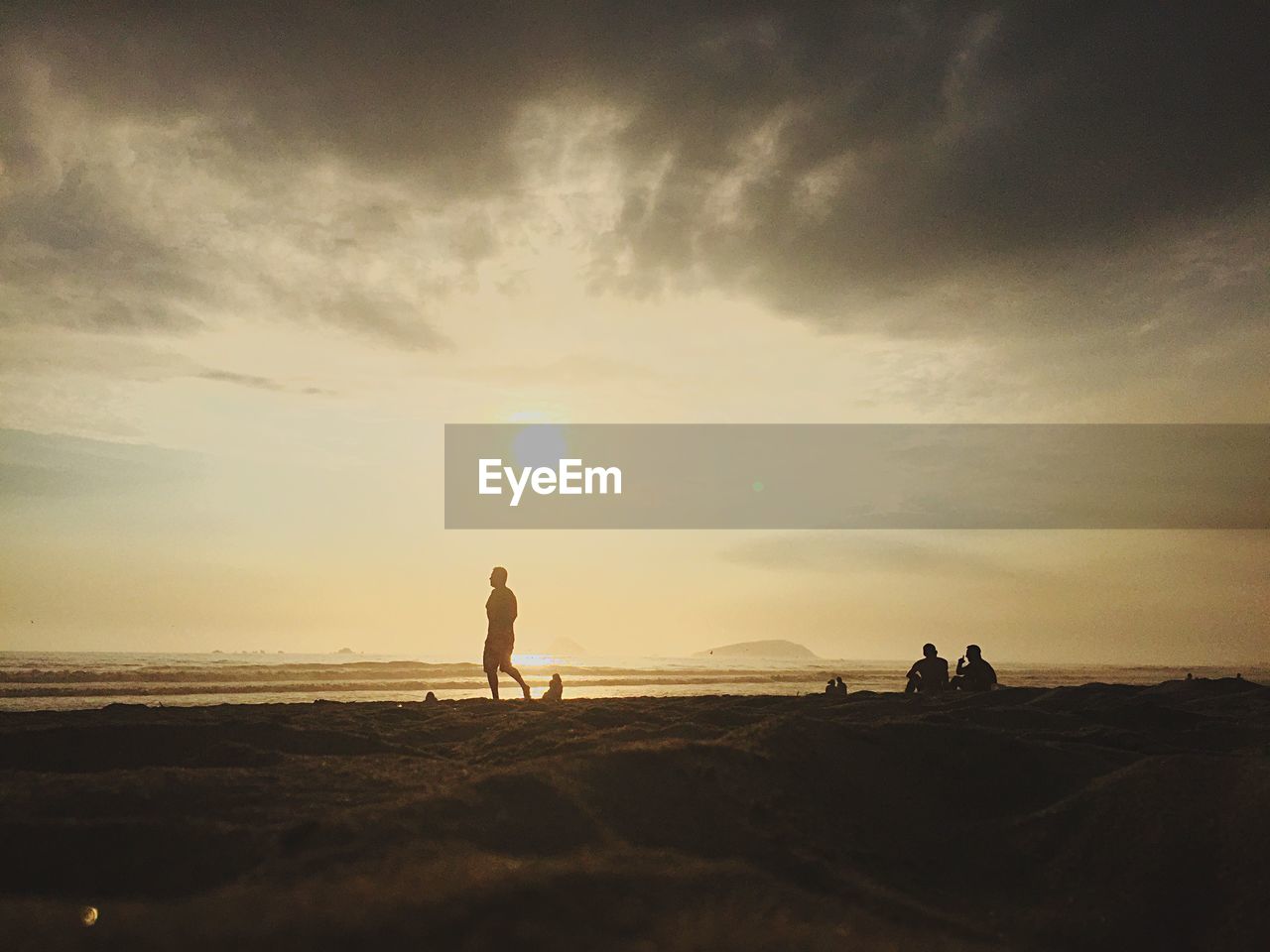 MEN ON BEACH AGAINST SKY