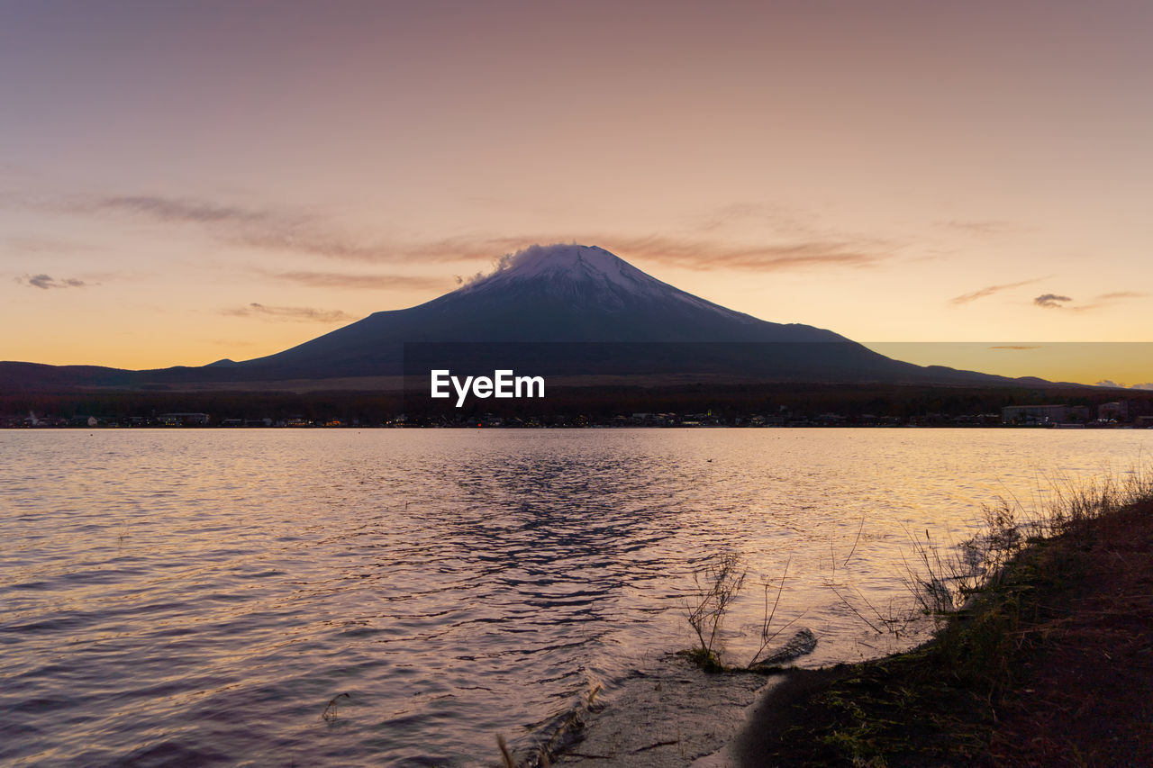 Scenic view of lake against cloudy sky during sunset