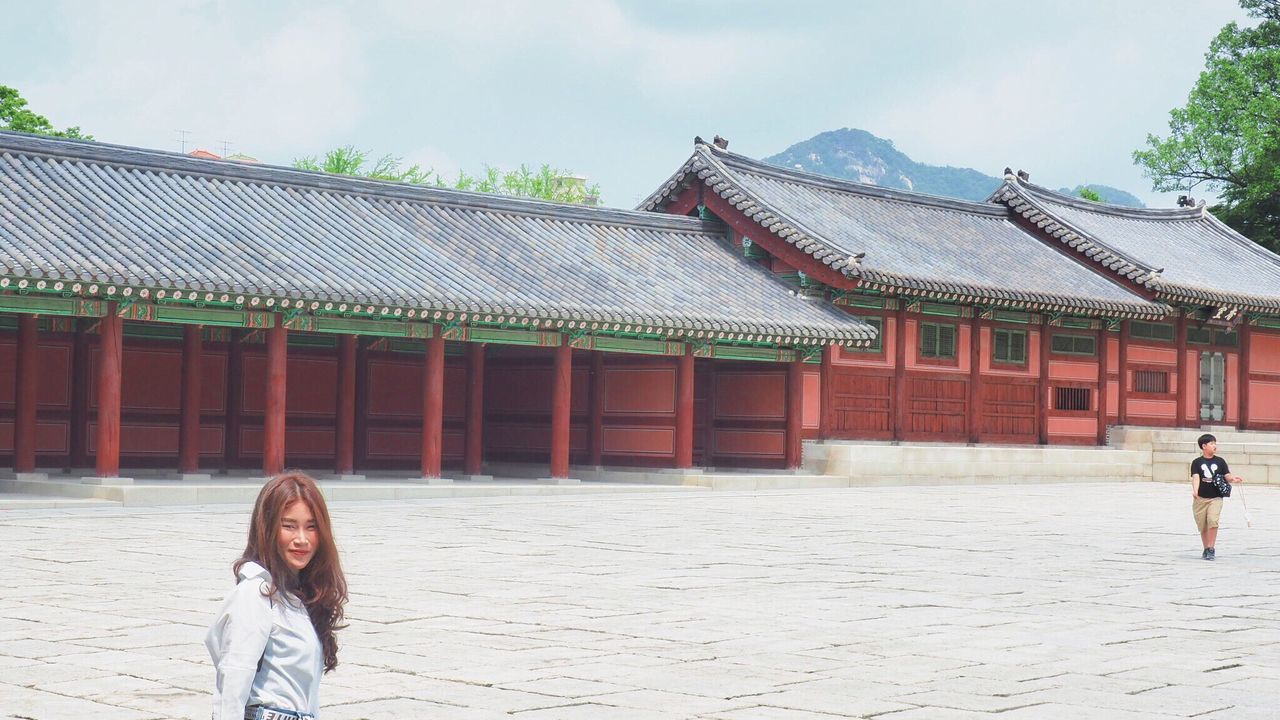 Woman standing by traditional building against sky