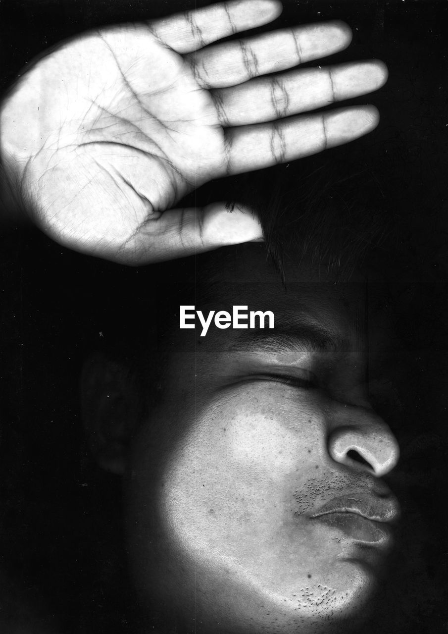 Close-up of eyes closed man seen through glass against black background
