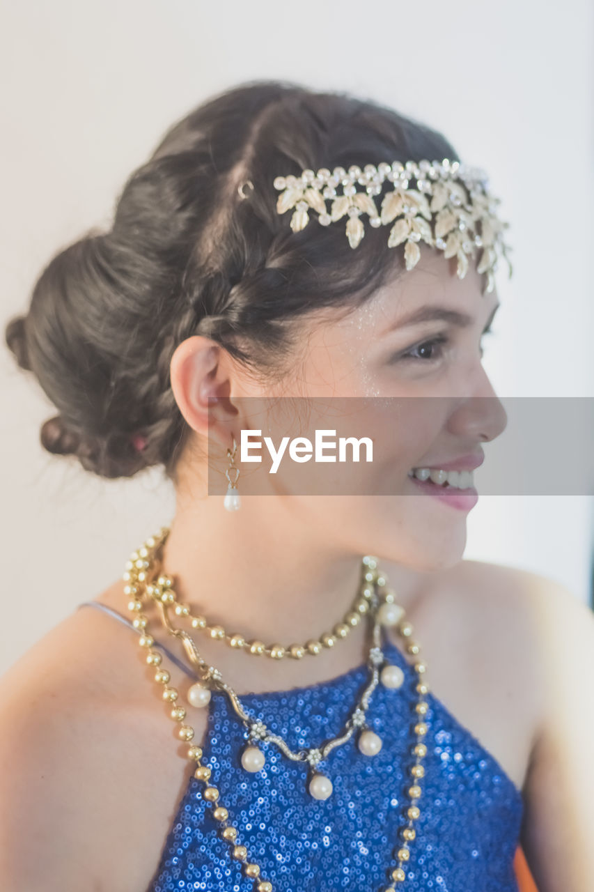 Close-up of smiling woman wearing jewelry against white background