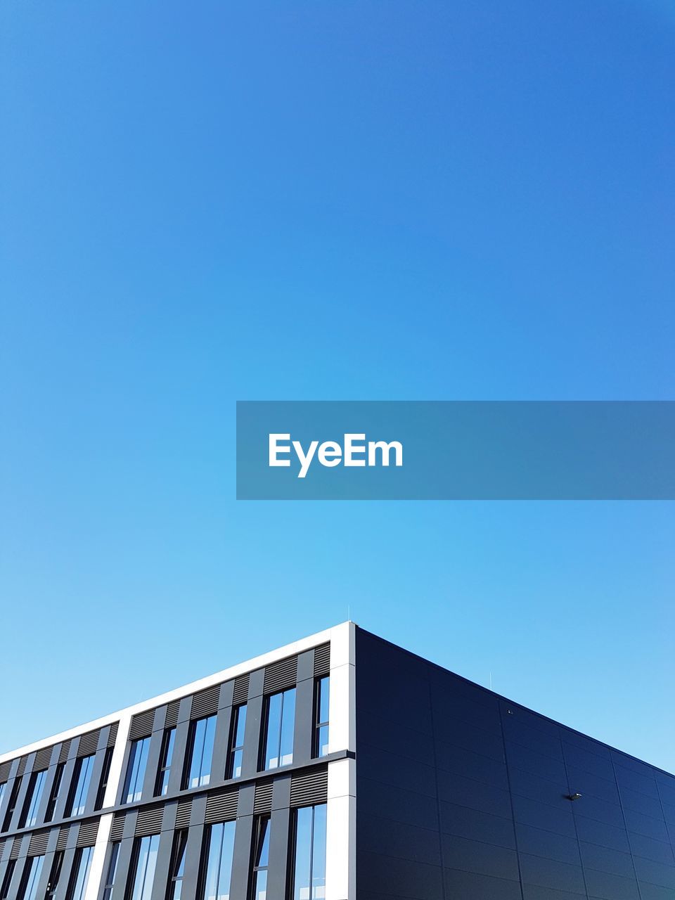 LOW ANGLE VIEW OF MODERN BUILDING AGAINST BLUE SKY