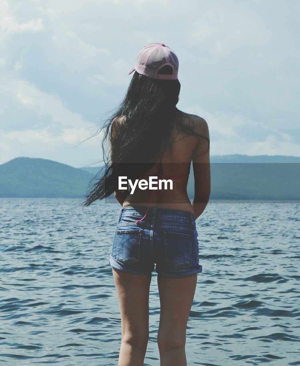 Young woman standing in sea against sky