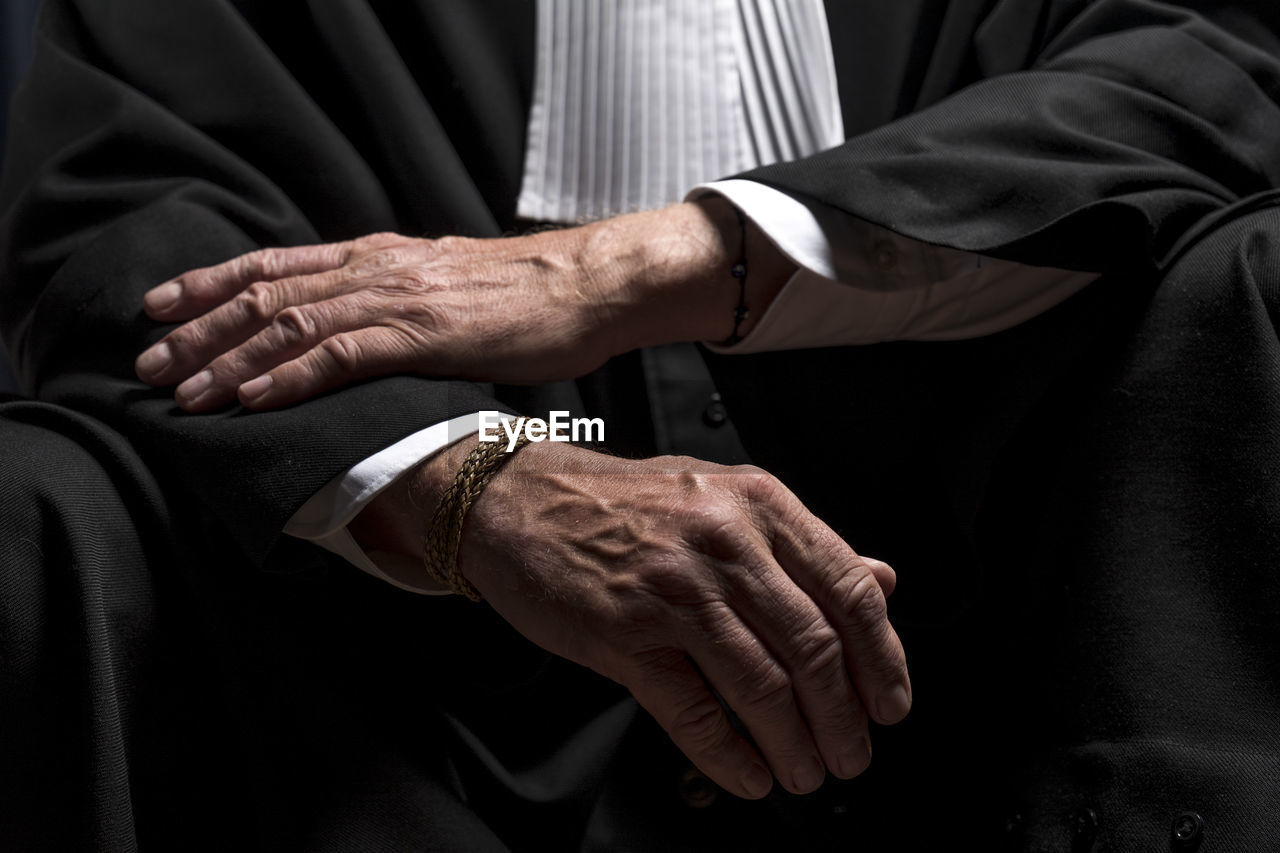 Midsection of lawyer standing against black background