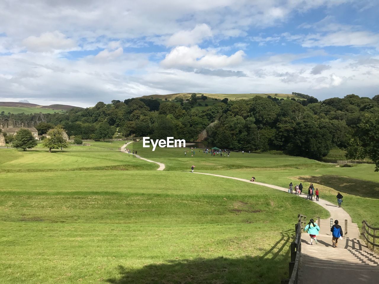 PEOPLE ON FIELD AGAINST CLOUDY SKY