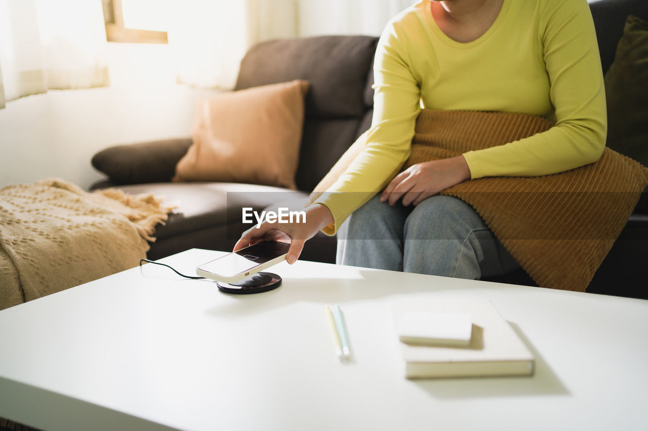 MIDSECTION OF WOMAN SITTING AT HOME